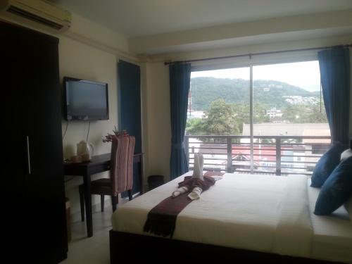 a bedroom with a bed and a window and a desk at The Green House in Kata Beach