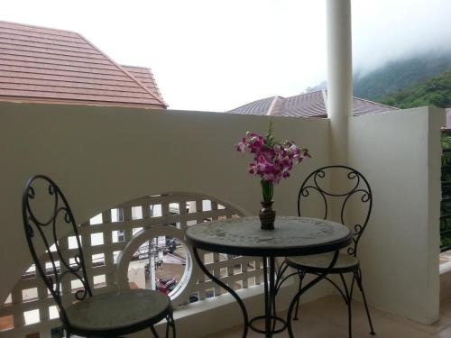 a table with two chairs and a vase of flowers on a balcony at The Green House in Kata Beach