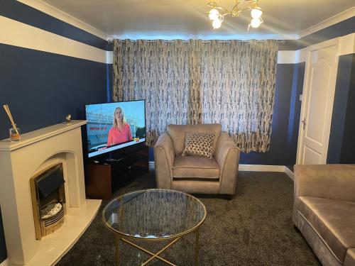 a living room with a tv and a couch and a chair at Stylish 3 bed house, private parking, garden and conservatory in Sheffield