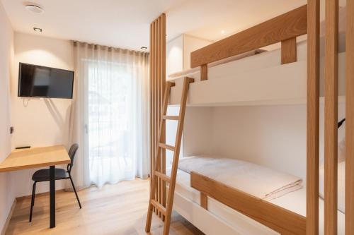 a bedroom with a bunk bed and a desk at VANEA - Alp Relax Guesthouse in Chienes
