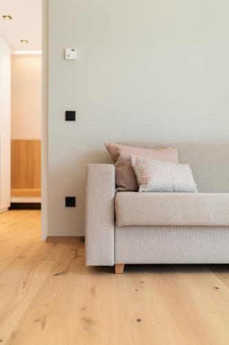 a couch in a living room with a wooden floor at VANEA - Alp Relax Guesthouse in Chienes
