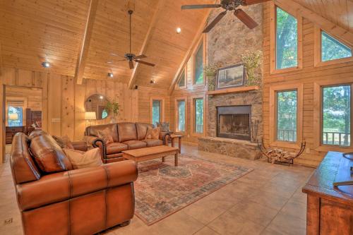 a living room with leather furniture and a stone fireplace at Country Cabin with Wraparound Deck and Views! in Springdale