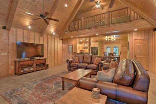 a living room with leather furniture and a flat screen tv at Country Cabin with Wraparound Deck and Views! in Springdale