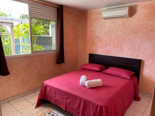 Un dormitorio con una cama con una manta roja y una ventana. en TAHITI - Fare Vairai Pool, en Faaa