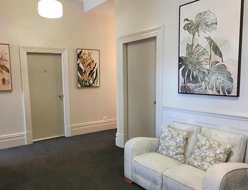 a living room with a couch and paintings on the wall at Work Stay at 123 in Dunedin