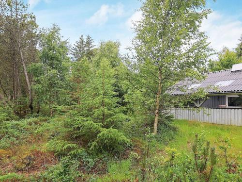 un patio con árboles y una valla y una casa en 5 person holiday home in lb k, en Ålbæk