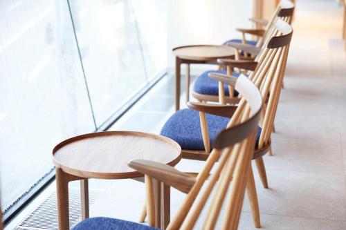 a row of wooden chairs and tables in a room at HOTEL AMANEK Kanazawa in Kanazawa