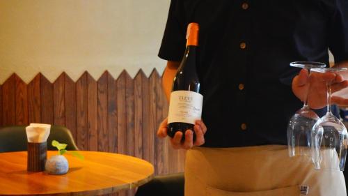 a man is holding a bottle of wine at karaarom hotel in Bangkok