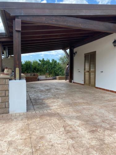 an open garage with a wooden roof and a brick patio at Loft incantevole con idromassaggio esterno privato in Patti