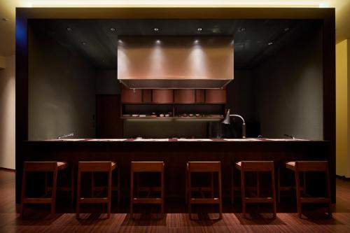 a kitchen with a bar with stools around it at HOTEL AMANEK Kanazawa in Kanazawa