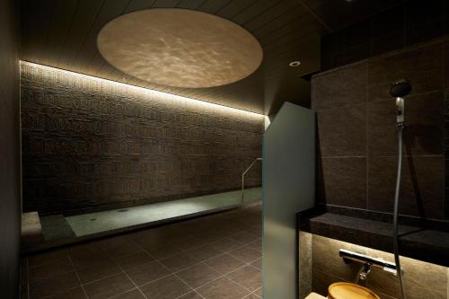 a bathroom with a toilet and a round light at HOTEL AMANEK Kanazawa in Kanazawa