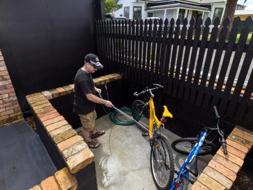a man is washing two bikes with a hose at Arista of Rotorua in Rotorua