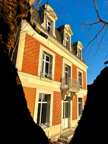 - un grand bâtiment en briques avec des fenêtres et un balcon dans l'établissement Maison Loire, à Blois