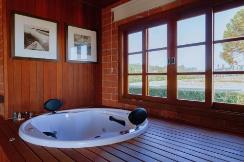 bañera grande en una habitación con ventanas en Pousada Chalés Por do Sol en Campos do Jordão