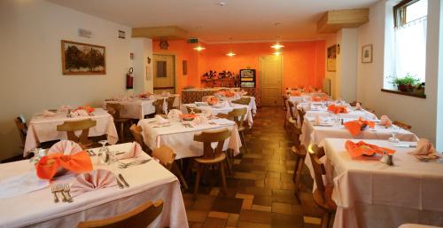 uma sala de jantar com mesas brancas e paredes cor de laranja em Albergo Sporting em Peio Fonti