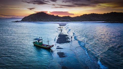 a small boat on the water with a beach at Coto Center Homestay in Dao Co To