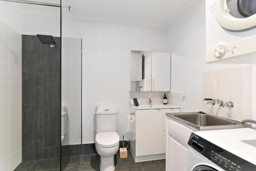 a white bathroom with a toilet and a sink at Stylish Townhouse, private courtyard walk to beach in Noosaville