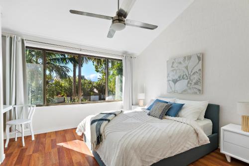 a bedroom with a bed and a large window at Stylish Townhouse, private courtyard walk to beach in Noosaville