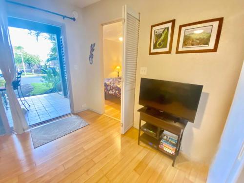 a living room with a flat screen tv next to a door at Beachfront 1 Bedroom Condo with Private Beach, Pool, Hot Tub in Pahala