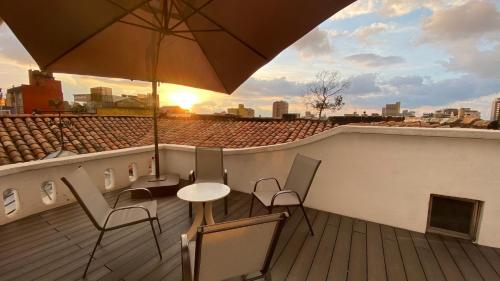 uma varanda com uma mesa e cadeiras e um guarda-sol em REPUBLICANA CASA HOSTAL - HABITACIÓN 6 CALIMA em Bogotá