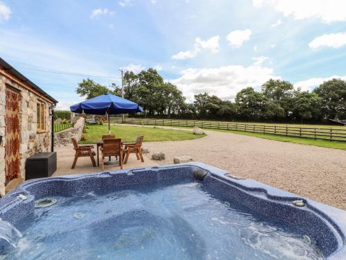 a hot tub with a table and chairs and an umbrella at The Old Cart House in Oswestry