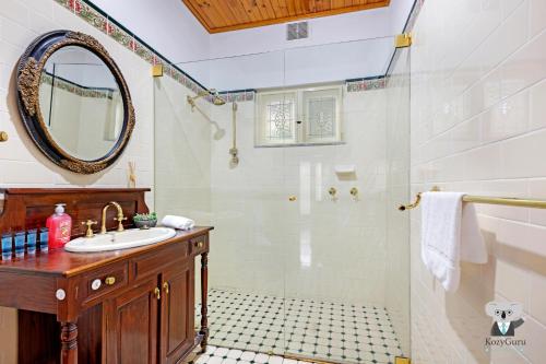 a bathroom with a sink and a shower with a mirror at KOZYGURU Campsie Oldie-but-goodie look 4 Bed House NCA011 in Sydney