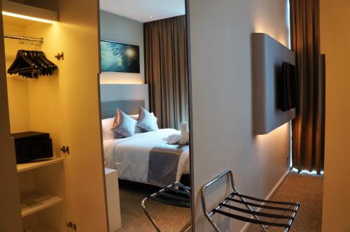 a hotel room with a bed and a mirror at Greens Hotel & Suites in Bintulu