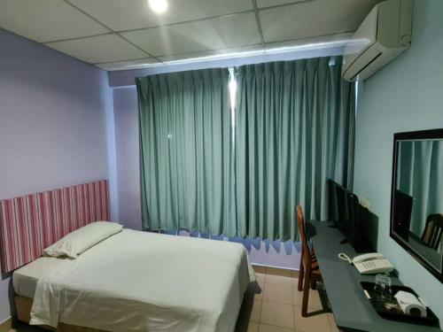 a bedroom with a bed and a desk with a computer at Century Hotel Inanam in Kota Kinabalu