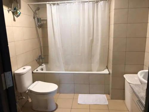 a bathroom with a toilet and a shower with a shower curtain at Central Park Residence in Jakarta