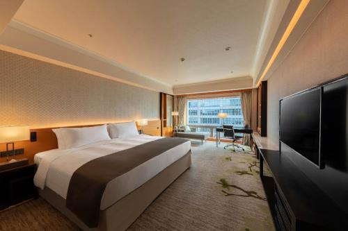 a hotel room with a bed and a flat screen tv at Hotel Metropolitan Premier Taipei in Taipei