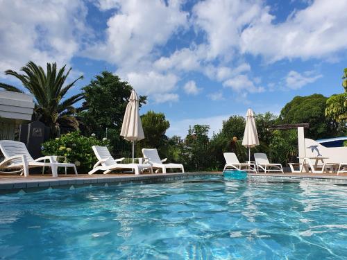 una piscina con sillas y sombrillas en Breakers Motel, en Whangamata