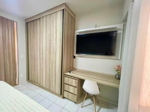 a bedroom with a bed and a television and a chair at Apartamento completo e encantador in Ribeirão Preto