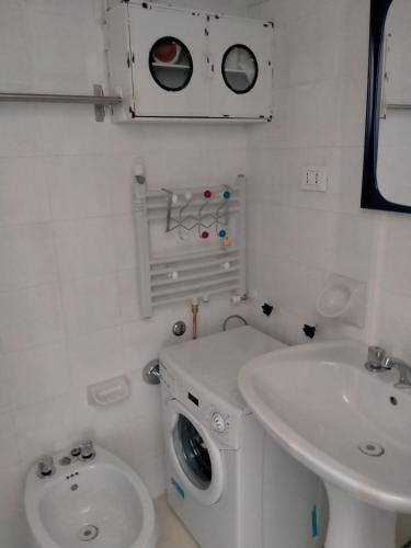 a white bathroom with a washing machine and a sink at Trilocale in dimora tipica in Montale