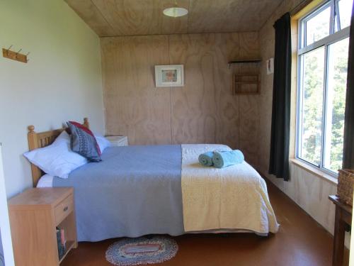- une chambre avec un lit et une fenêtre dans l'établissement Mulberry Grove Retreat, à Tryphena