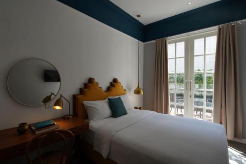 a bedroom with a bed and a mirror and a window at THE FOLK in Kejayan