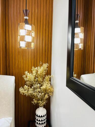a vase of flowers on a table next to a mirror at Lou- Mesaverte Residences in Cagayan de Oro