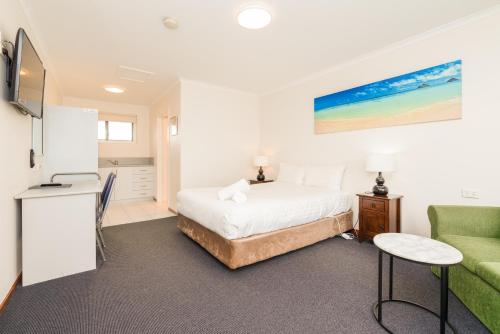 1 dormitorio con 1 cama y 1 sofá verde en Seasonal South Motel & Function Centre, en Ulverstone