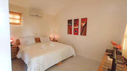 a bedroom with a white bed and two paintings on the wall at Alona42 Resort in Panglao