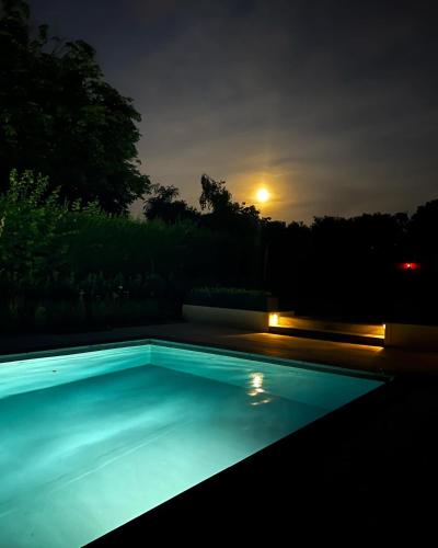 a swimming pool at night with the moon in the background at Vakantiewoning De Winning in Houthalen-Helchteren