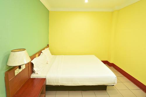 a small bedroom with a bed and a lamp at Mandarin Inn in Mukah