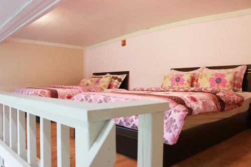 a bedroom with two beds with pink and yellow pillows at Dreaming Forest Pension Seogwipo in Seogwipo