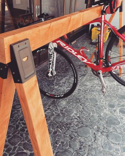 a bike parked under a wooden bench with a meter at ゲストハウス　華屋 (guest house HANAYA） in Sado