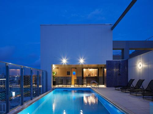 una piscina sul tetto di un edificio di notte di hotel androoms Naha Port a Naha