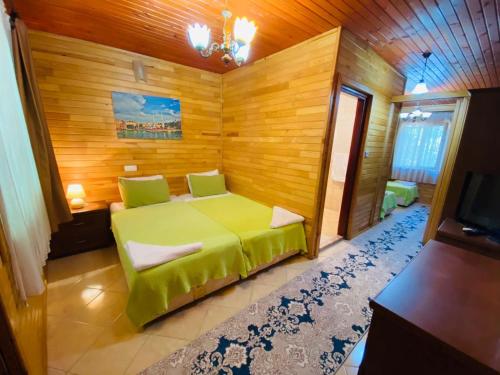 a bedroom with a green bed and wooden walls at Canada Hotel & Bungalows in Cıralı