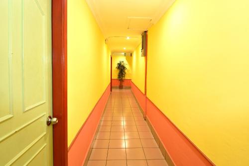 a hallway with yellow and orange walls and a plant at Mandarin Inn in Mukah