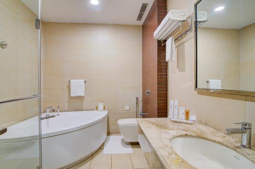 a bathroom with a tub and a toilet and a sink at Hotel Home In By Amrik Sukhdev in Sonīpat