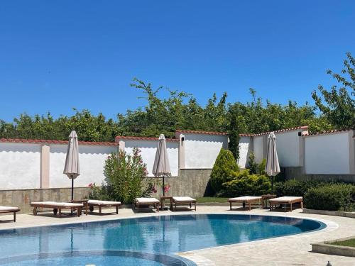 a swimming pool with umbrellas and tables and chairs at Villa Mia in Sozopol