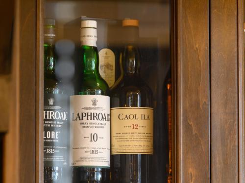 three bottles of wine in a wooden cabinet at Tabist Miya Yokkaichi Suizawa in Suizawa