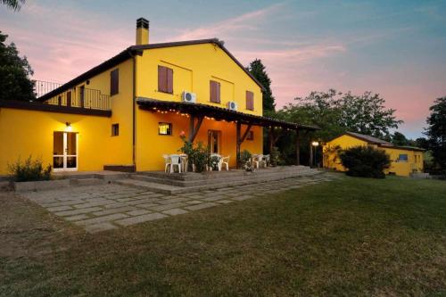 a yellow house with tables and chairs in a yard at La Meriggia Senigallia Agriturismo in Ancona