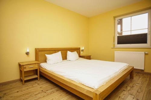 a bedroom with a bed with white sheets and a window at Schicke FeWo mit Terrasse, gratis Nutzung vom AHOI Erlebnisbad und Sauna in Sellin - Haus De niege Wech FeWo 02 in Thiessow